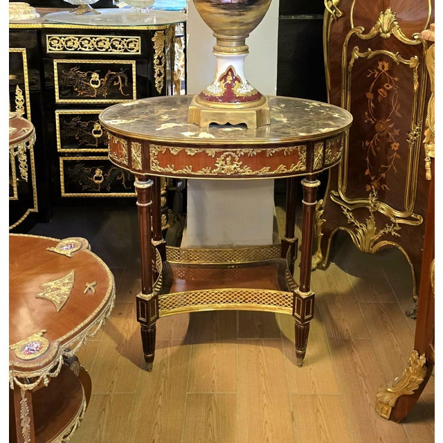 A sophisticated French Louis XVI-inspired coffee table combining rich wood craftsmanship with an elegant marble top and...