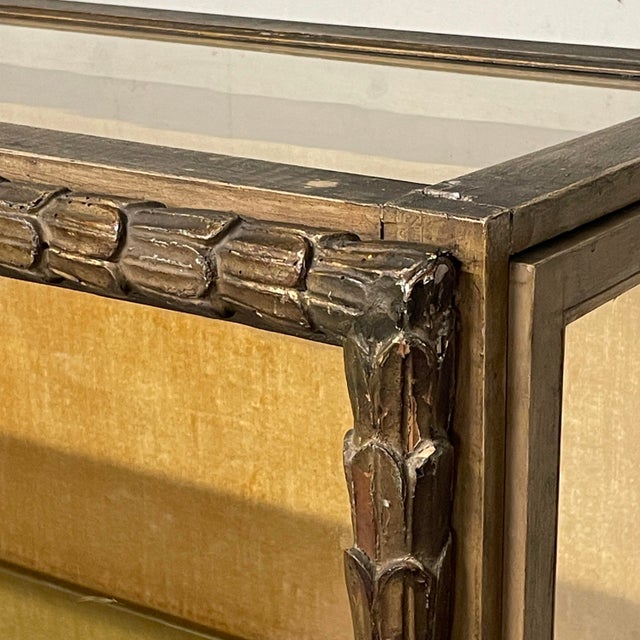 A 1940s display cabinet with a carved and gilded wooden frame, featuring a ribbed design reminiscent of Renaissance or...
