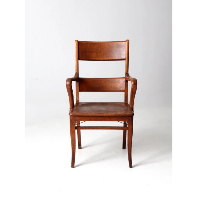 This is an antique oak arm chair circa 1890s. The wood office chair features beautiful lines with curving arms and legs...