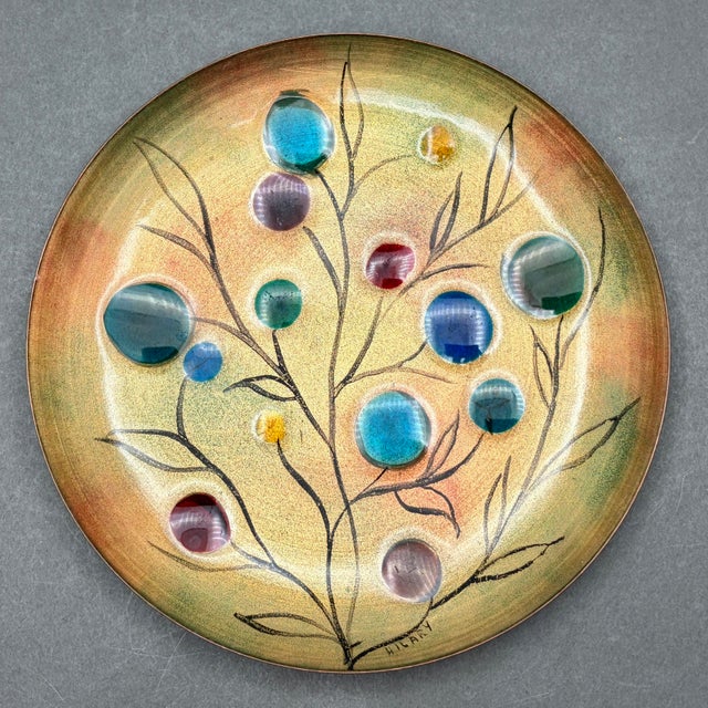 • Hilary enamel on copper decorative plate featuring a colorful “Tree of Life” botanical design with raised glass cabochon...
