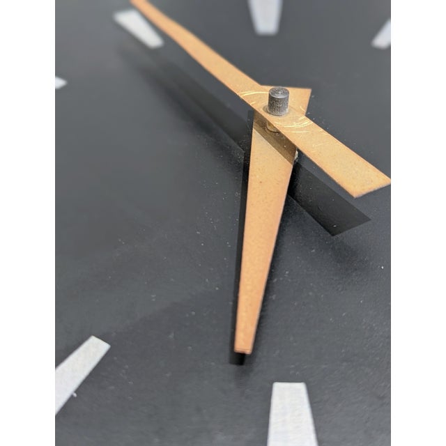 Square electric wall clock featuring a dark wood face with metal sunburst indices and brass hands. Plug-in synchronous...