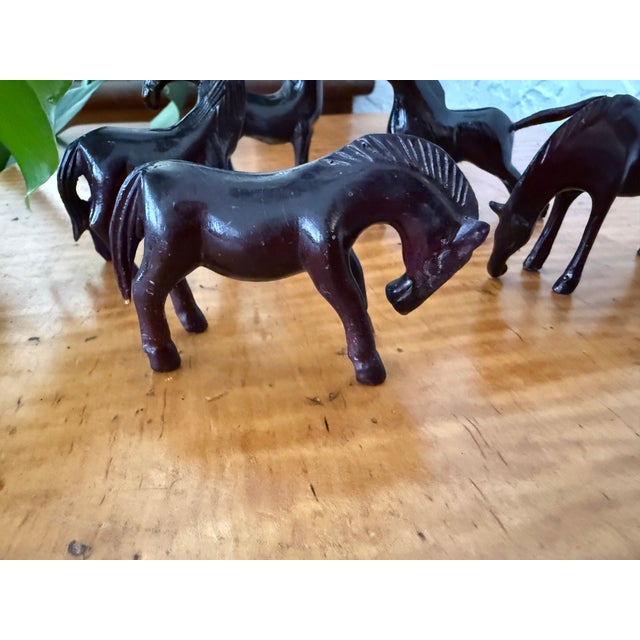 Beautiful set of five small horse figurines, carved from a dark, dense wood with a smooth polished finish. The horses...