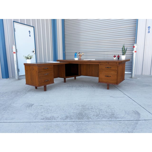 Mid-Century Modern Walnut L-Shape Executive Desk designed and manufactured in the United States, circa 1960s. This...