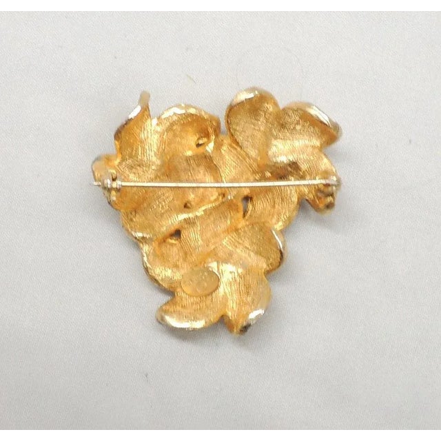 This is part of Chairish’s Costume Jewelry assortment. 1960s three goldtone textured flowers with small round clear...