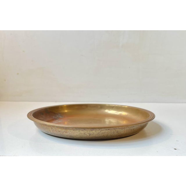 A solid bronze charger, dish or flat bowl with a reddish patina. Designed and manufactured by Tumulus Dania in Denmark...