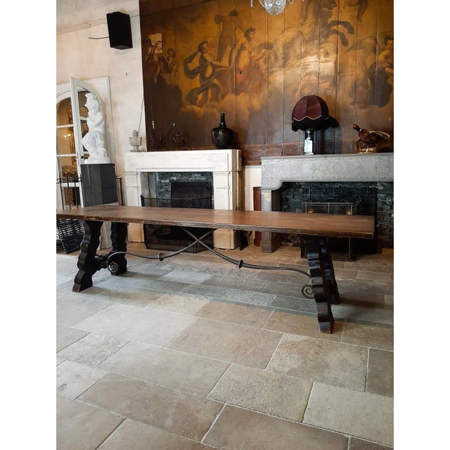 A sturdy and elegant large 19th century Spanish wooden dining table with worn patina and beautiful hand-forged iron...