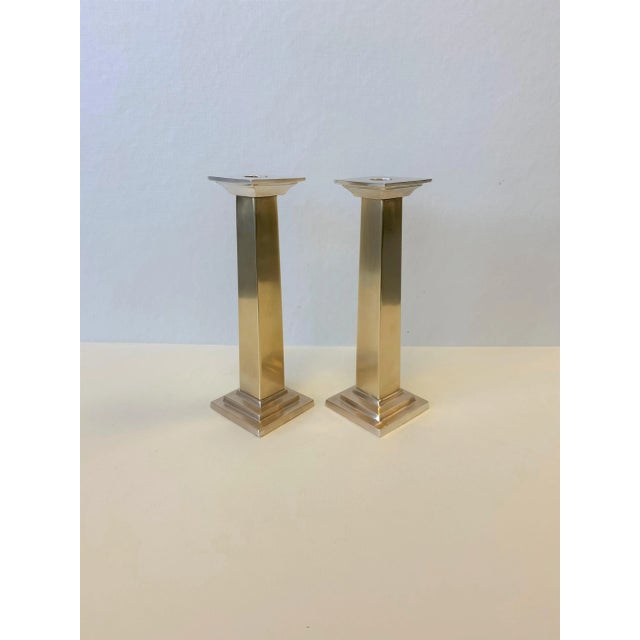 This pair of neoclassic metal pillar candlesticks features a classic design. Silver toned cascading column caps compliment...