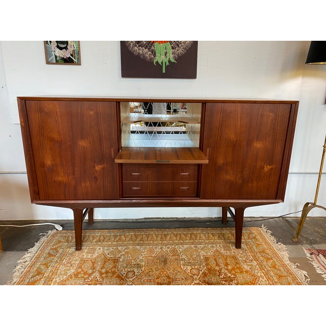 Danish modern solid teak sideboard or credenza with ample storage options. Features two sliding doors, which open to...