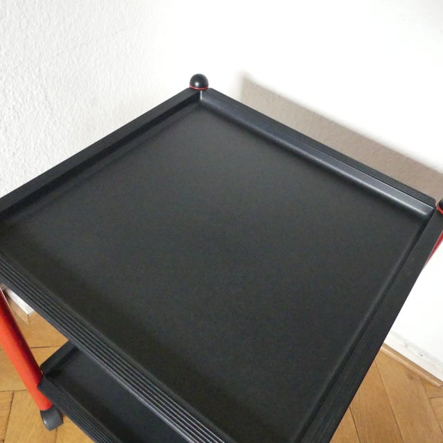 Italian postmodern side table with a red lacquered metal frame and two black plastic surfaces. Designed by Boccato,...