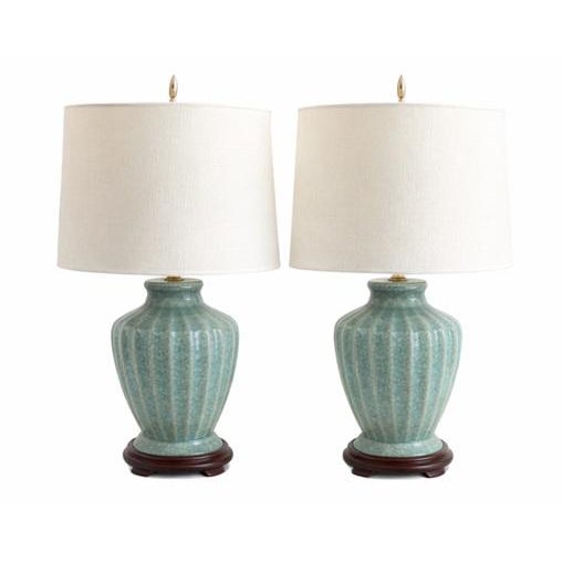 A refined pair of celadon crackle-glazed porcelain table lamps featuring softly ribbed baluster forms and a luminous blue-...