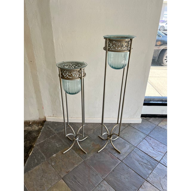 Elegant decorative pair of Mexican blown-glass vessels in graduated-height metal stands. Each pale aqua glass bowl...