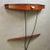 Refined Italian-designed wall console table from the 1960s. Mahogany frame with black glass top, drawer, and lower shelf...