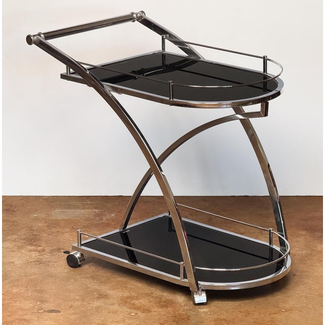 A fine vintage Art Deco two-tiered drinks cart or bar trolley from England, featuring a polished chrome frame, with two...