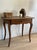Walnut on slender cabriole legs that splay outward at the toes, the top with rounded corners worn pale where hands rested....