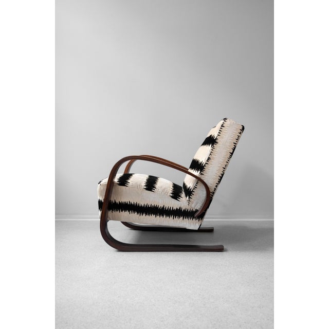 A very elegant Art Deco armchair with curved wooden armrests, recently renovated and reupholstered in a high-quality...