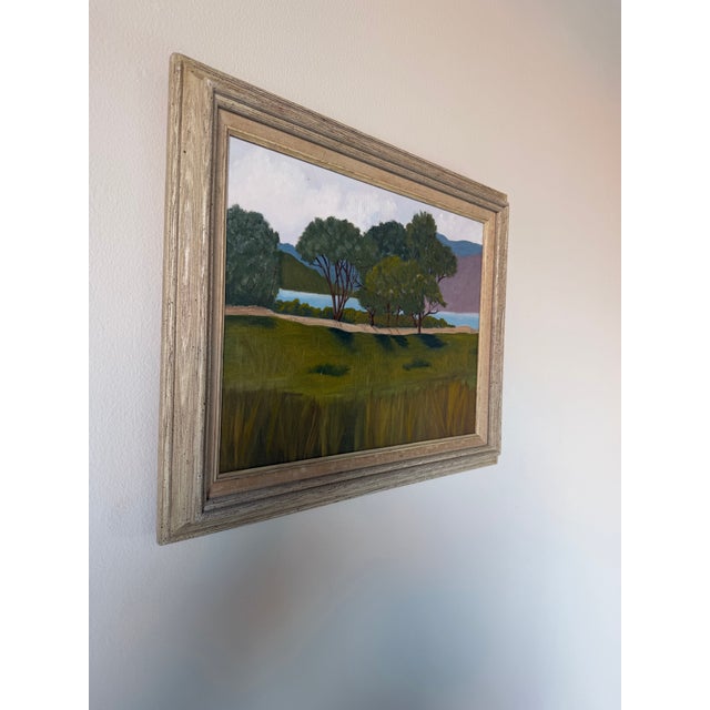 Charming 1980s vintage landscape oil painting on canvas depicting a tranquil lakeside scene with lush green trees, rolling...