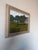 Charming 1980s vintage landscape oil painting on canvas depicting a tranquil lakeside scene with lush green trees, rolling...