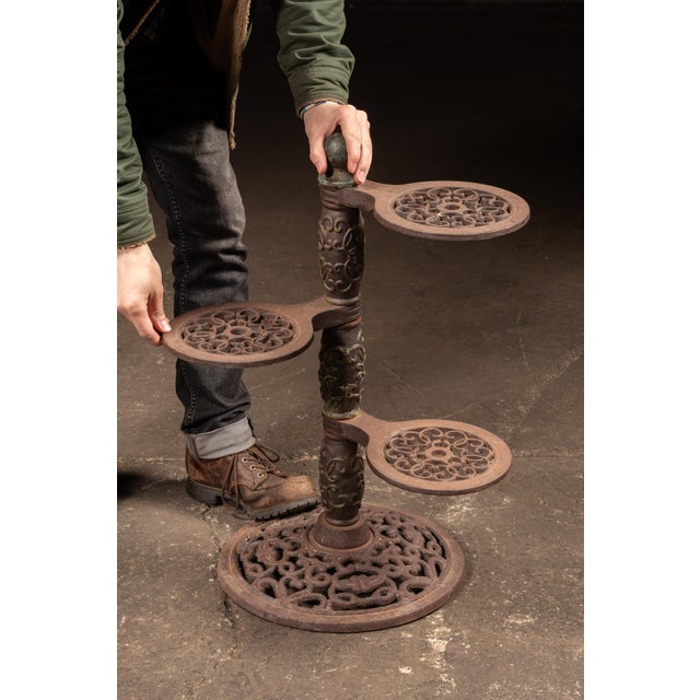 Early 20th-century cast iron three-tier plant stand featuring three independently adjustable circular platforms arranged...