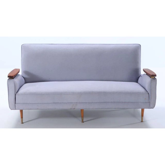 A restored sofa with floating wood arms and metal mounts circa 1960. Having new fabric.
