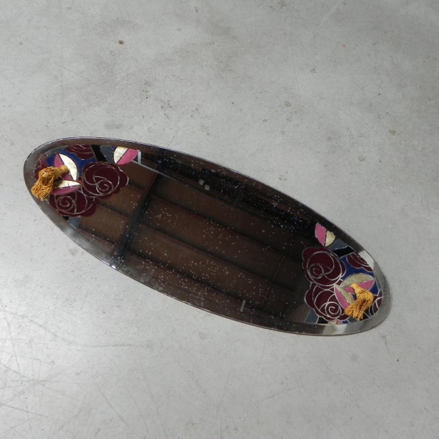 The floral decoration is on the back of the mirror. Height: 39 cm. Width: 99 cm. Depth: 5 cm. The mirror has some small...