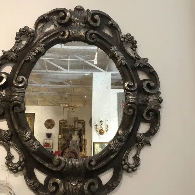 Carved wooden oval mirror featuring acanthus leaves in a bolo and silver leaf finish with aged glass. Italy.