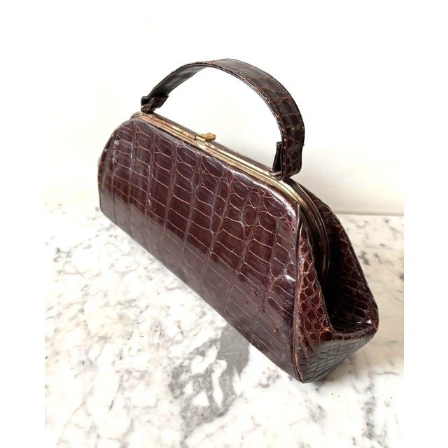 Lovely vintage leather handbag with faux crocodile print. Includes a small pocket mirror and coin purse. Metal top...
