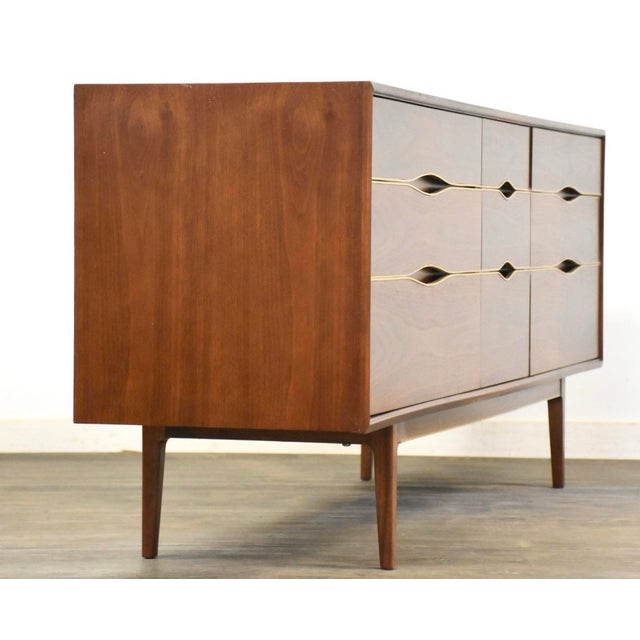 A mid century modern walnut nine drawer dresser with brass accents. Professionally refinished. 77.5” wide. 19” deep....