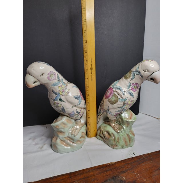 This matched pair of Mid-Century Modern WBI Chinese Parrot Figurines in Famille Rose style feature a floral pattern with...