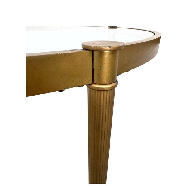 A pair of round side tables crafted in a timeless neoclassical style, featuring gilt metal frames with clean,...