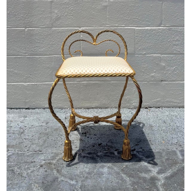 Elegant vintage vanity stool featuring a sculptural twisted gilt metal frame with graceful curves and a romantic heart...