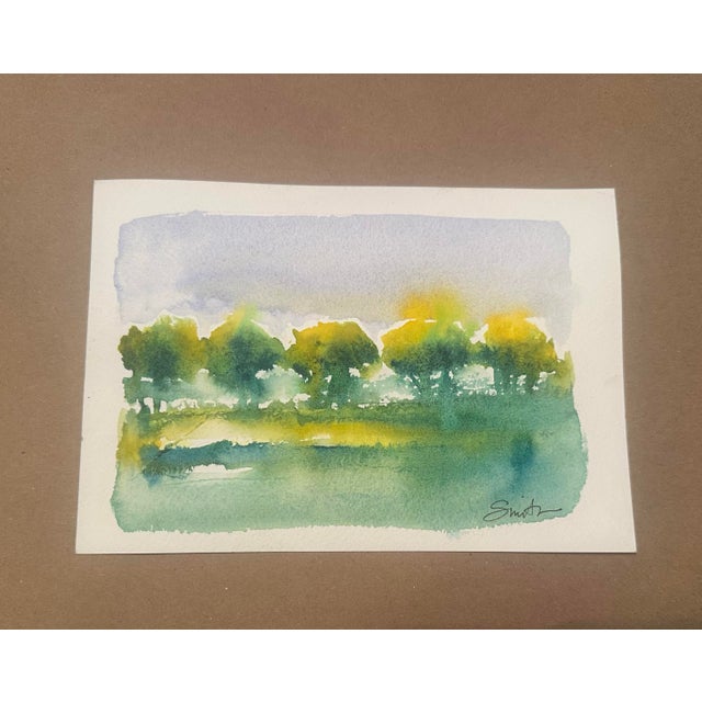A luminous original watercolor landscape capturing a quiet meadow beneath a softly painted summer sky. A row of loosely...