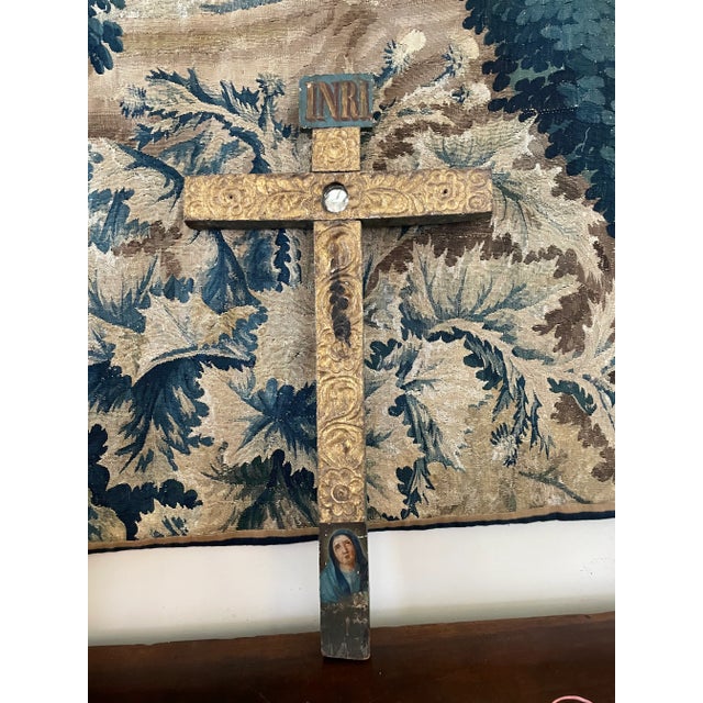 A polychrome Latin crucifix, with a tiny circular mirror at the intersection of the arms and a portrait of the Virgin Mary...