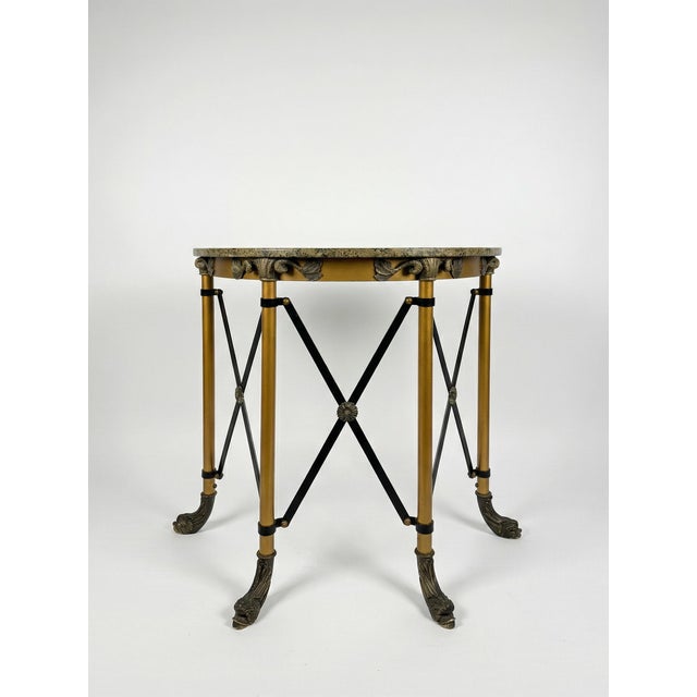 A striking demilune console table with a speckled granite top resting on a sculptural neoclassical-style base. The legs...