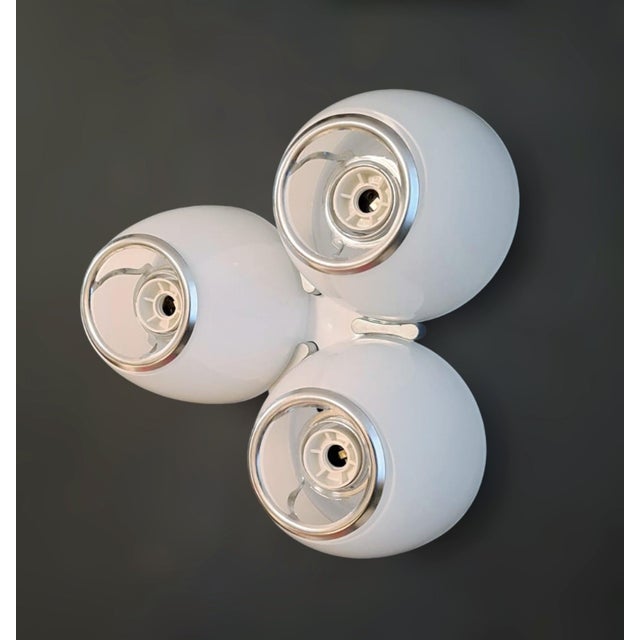 Italian wall light model "DELTAKALIAS" with three white Murano glass diffusers forming a triangular shape, mounted on...