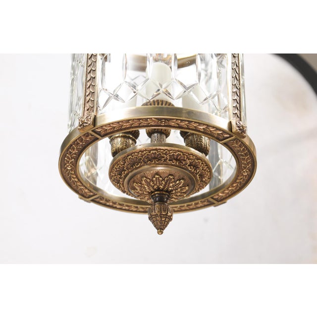 Elegant neoclassical lantern crafted in patinated bronze with faceted crystal panels and refined foliate detailing. The...