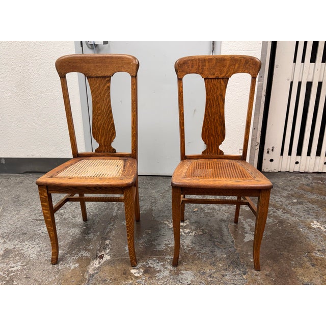 Design Plus Gallery presents a pair of Vintage Limbert Style Oak Cane Side Chairs. The chairs have arched crest rails,...