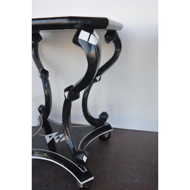 Two white and black side tables made of coconut shells. Triangle design on the top and the base of the side tables.