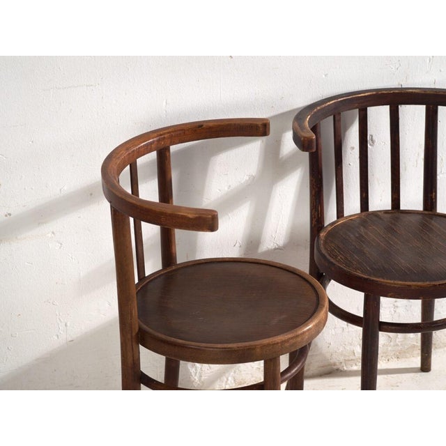 A set of two antique armchairs in bentwood, with a horseshoe back wrapping into the arms, over vertical splats and a...