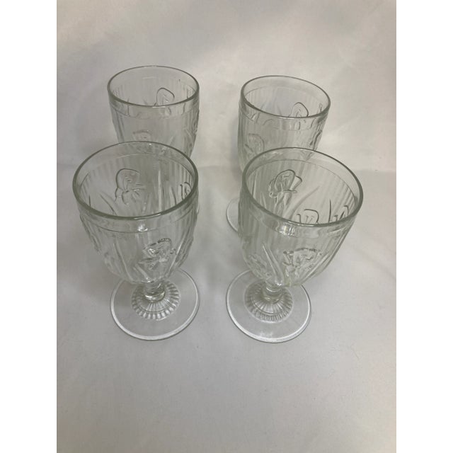 A set of 4 lovely vintage depression glass goblets. They are the clear floral“Iris” pattern made by Jeanette Glass Company...