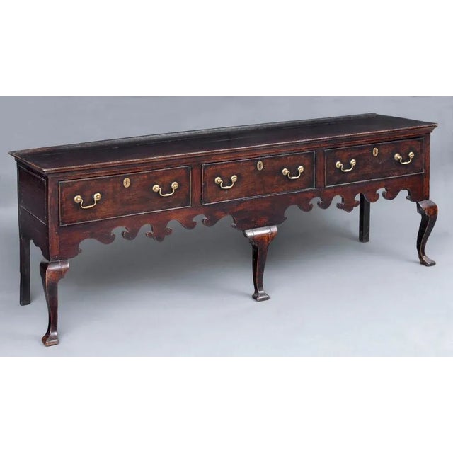 George II oak dresser with bold Gothic shaped apron on the front and sides, three cockbeaded drawers, three squared...