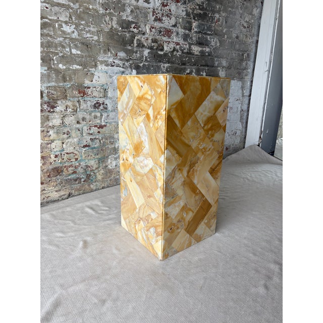 A striking antique pedestal clad in richly variegated golden stone, arranged in an expressive geometric mosaic pattern....