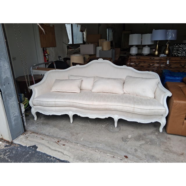 Elegant and romantic, this French Louis XV–style sofa features a beautifully shaped exposed-wood frame finished in a...