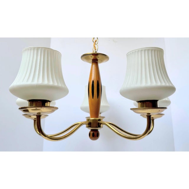 Lightweight circa-1960s brass chandelier with black-painted wood accent pieces and fluted frosted-glass shades. In very...