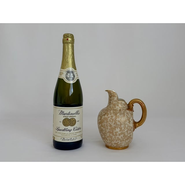Antique Royal Worcester porcelain jug dating to 1887, featuring an ivory-toned body covered in intricate gilt floral and...