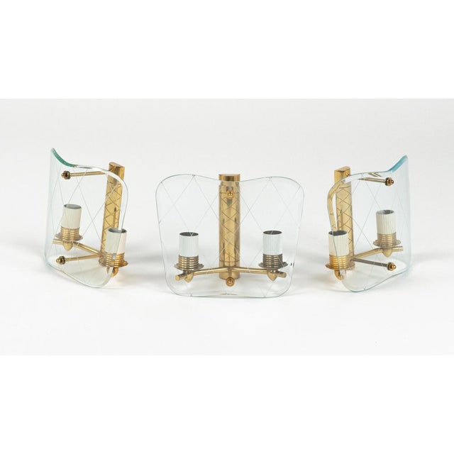 Midcentury amazing set of three sconces in brass and curved glass in the style of Pietro Chiesa for Fontana Arte. Made in...