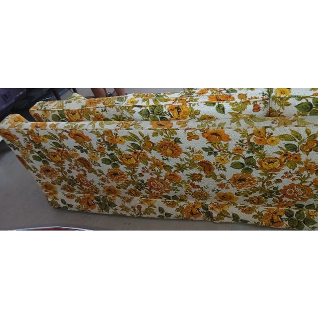 This vintage 1970s floral sofa features a vibrant orange and yellow floral pattern against a neutral background. The piece...