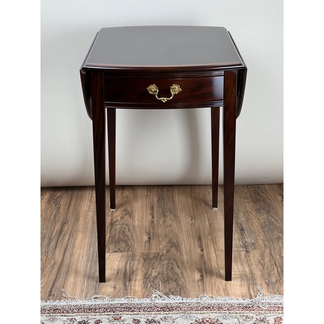 A beautifully crafted vintage Federal style mahogany end table by Stickley, featuring a classic drop-leaf design with a...