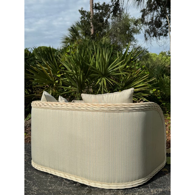 Beautiful wicker loveseat featuring a classic woven wicker frame paired with a light tan upholstered seat cushion and...