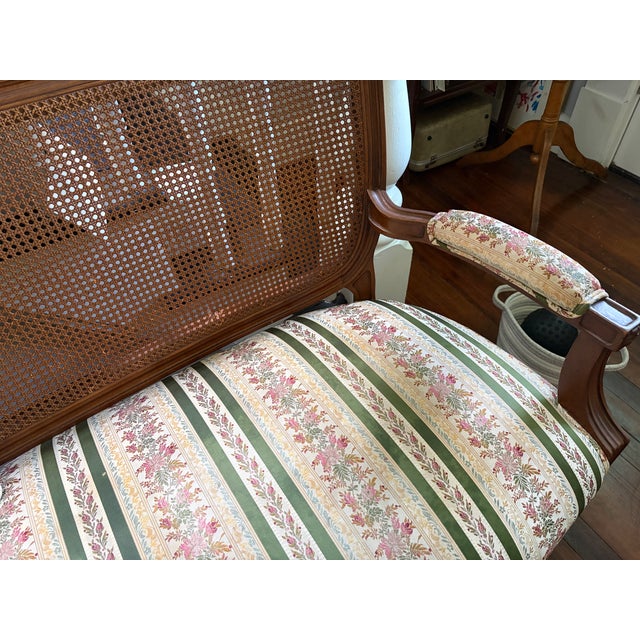 A vintage French Provincial Louis XVI style cane back settee circa mid-20th century, featuring cane, solid wood frame,...