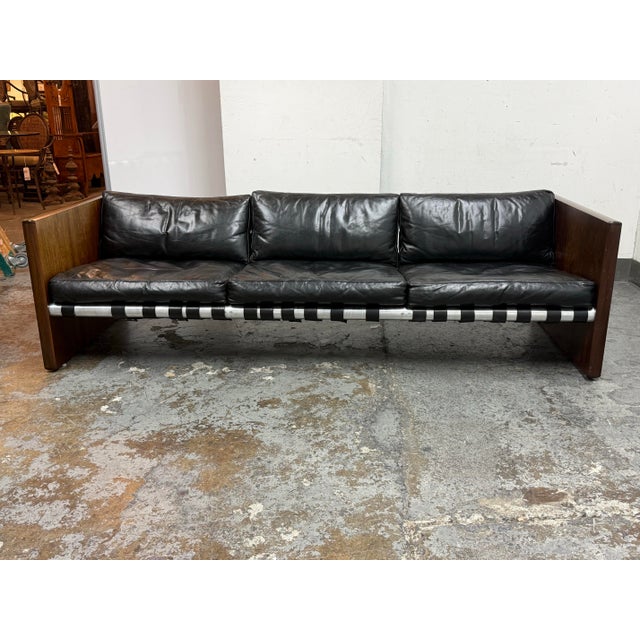 Design Plus Gallery presents a Circa 1970's Rosewood + Black Leather Strap Sofa from Selig Furniture. Architectural lines...